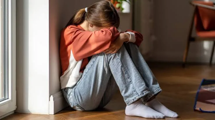 A distressed child sitting on the floor with knees drawn up and face buried in their arms after a hard day